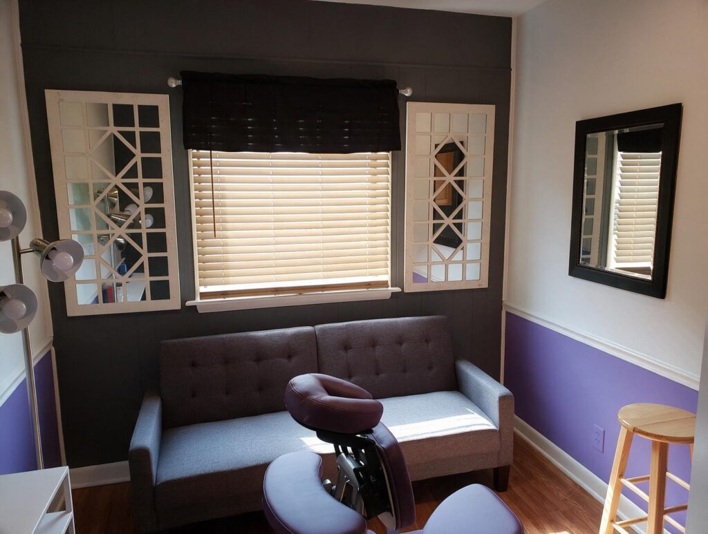 2208 featured 1791929654: carolina scalp center Empty treatment room with a grey sofa under a window with wooden blinds, mirrors, purple chair